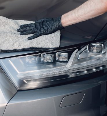 Man in a garage. Worker polish a car.